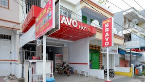A hotel named AVO with a red and white facade, a green door, and a signboard for Hotel Bravo. - RedDoorz @ Hotel Bravo Pantai Kamali Bau Bau (Bau-Bau)
