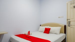 A neatly made bed with a red and white bedspread, a red pillow, and a white pillow. - RedDoorz @ Hotel Bravo Pantai Kamali Bau Bau (Bau-Bau)