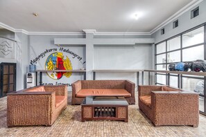 Una habitación con muebles de mimbre, una mesa y una pared con un logotipo y texto.