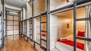 A corridor with bunk beds, wooden flooring, and a ceiling with a light fixture. - RedDoorz Hostel near Stadion Mandala Krida Yogya (Yogyakarta)