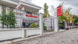A gated property with a sign reading "RedDoorz" and a RedDoorz signboard indicating amenities. - RedDoorz Hostel near Stadion Mandala Krida Yogya (Yogyakarta)