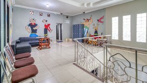 A waiting area with a staircase, a sofa, and a mural on the wall. - RedDoorz Hostel near Stadion Mandala Krida Yogya (Yogyakarta)
