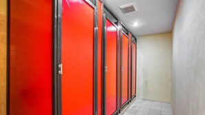 A row of red lockers in a hallway with white tiled flooring.