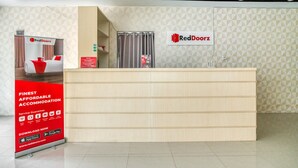 A reception desk with a RedDoorz sign, a promotional banner, and a patterned wall.