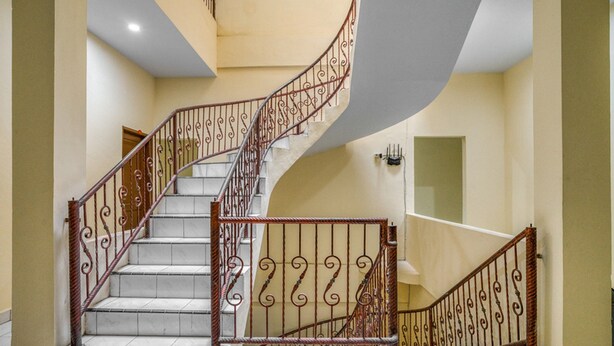 A spiral staircase with ornate metal railings and a tiled floor.