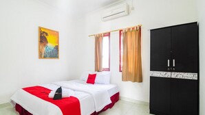 Een hotelkamer met een bed, een kledingkast, een raam met gordijnen en een airconditioning.