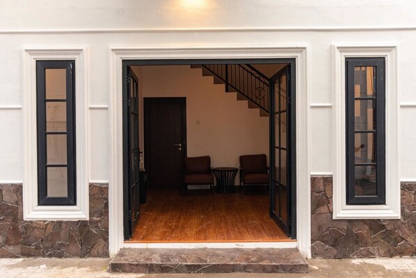 A building entrance with a wooden floor, a staircase, and two chairs. - RedDoorz @ Binjai (Medan)