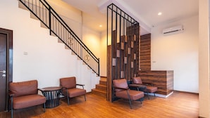 A lobby with a wooden staircase, leather seating, and a reception desk.
