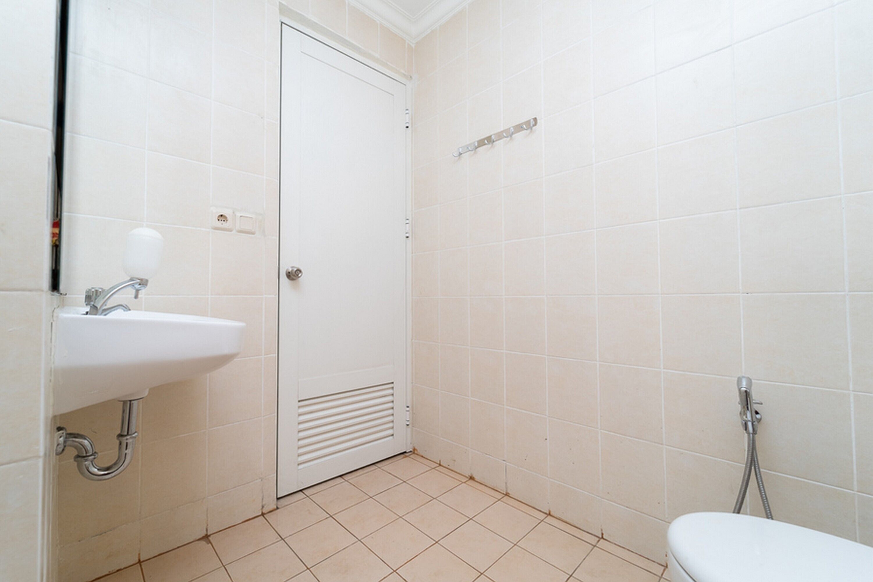 Un baño pequeño y limpio con azulejos blancos, un lavamanos, un inodoro y una ducha.