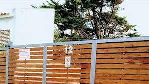A wooden fence with a metal gate, a sign with a phone number, and a 'No Entry' sign. - Hermoso Duplex 2 amb. 1 costa  cochera lavarropas,impecable (Mar del Plata)