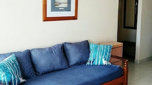A blue sofa with a wooden frame and a picture frame on the wall. - Hermoso Duplex 2 amb. 1 costa  cochera lavarropas,impecable (Mar del Plata)