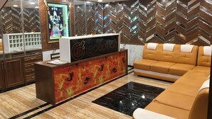 Un área de recepción con mostrador, un sofá y una pared decorativa con diseño en zigzag.