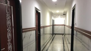 Un pasillo con suelo de mármol, paredes blancas y puertas con diseños decorativos.
