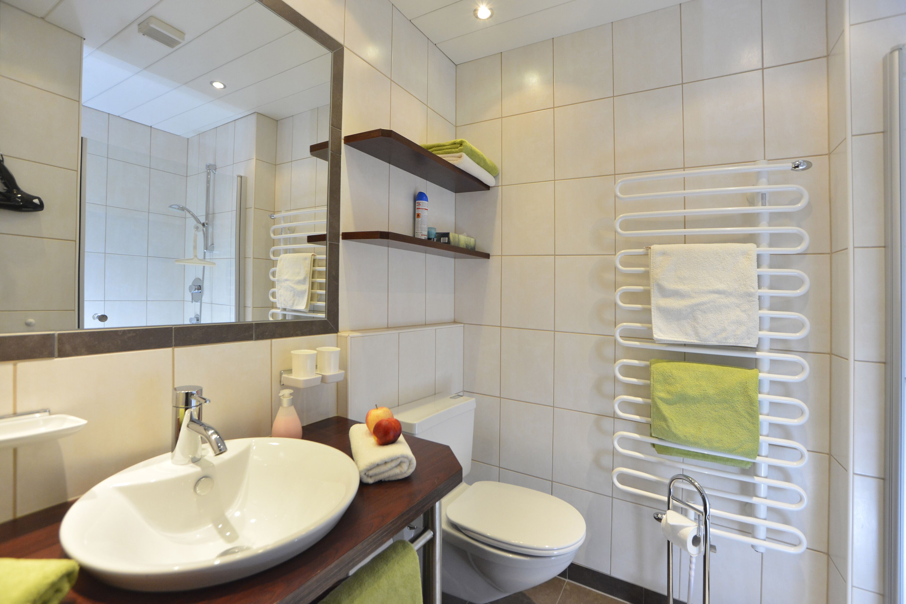 A modern bathroom with a large sink, toilet, and a towel rack with multiple towels.