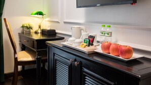 A hotel room with a dining area featuring a table set with a coffee pot, cups, a tray with apples, and bottled water. - My Gallery Boutique Hotel & Spa (Sa Pa)