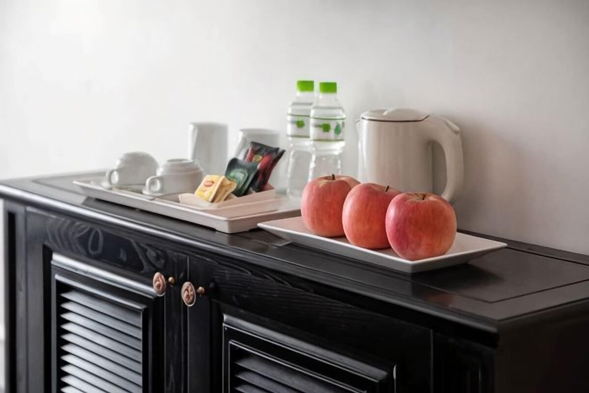 Una encimera de cocina con una cafetera, una botella de agua y un plato con manzanas.