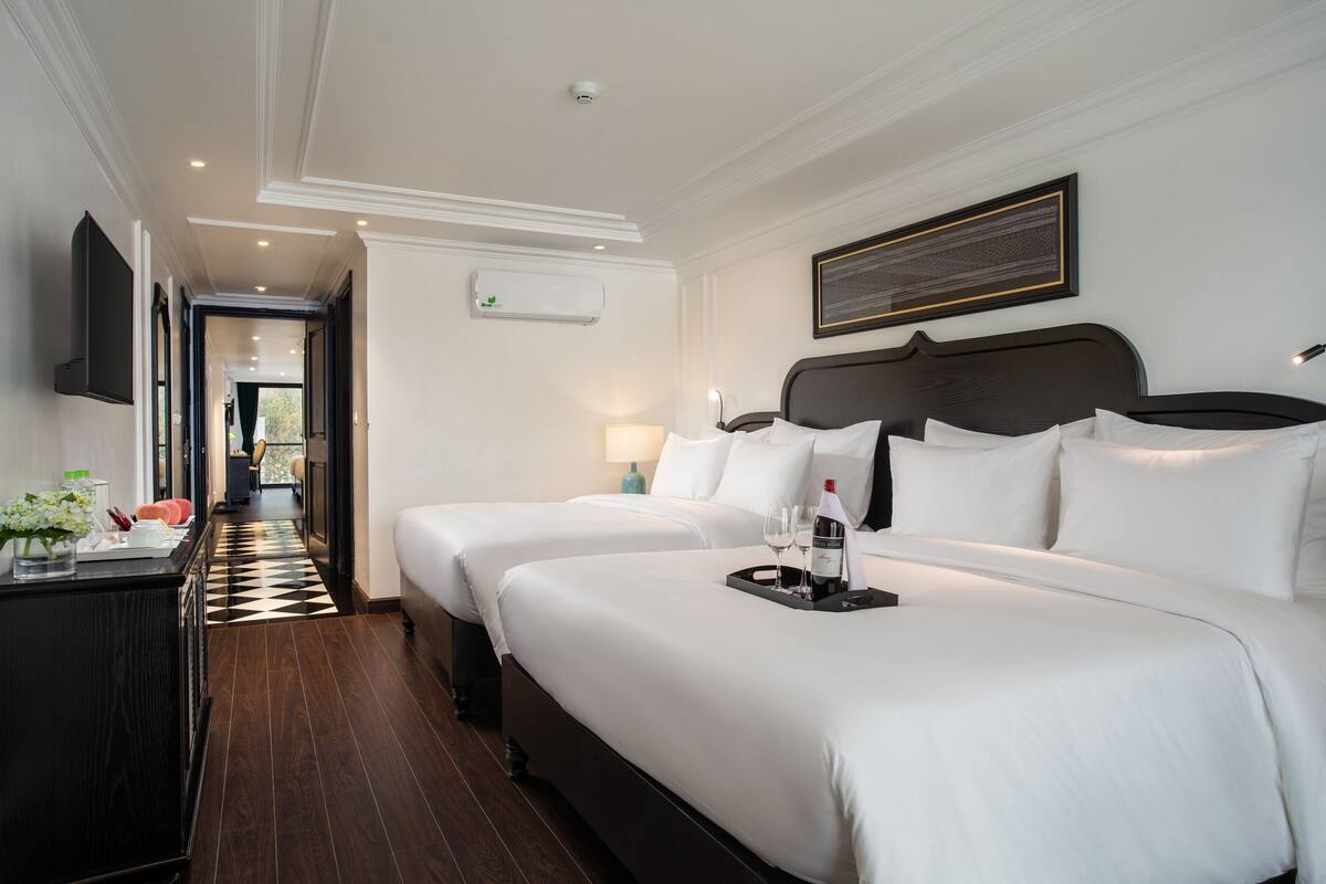 A hotel room with two beds, a flat-screen TV, a minibar, and a view of the outdoors.