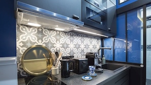 A modern kitchen with a patterned backsplash, a built-in oven, and a stainless steel range hood. - Le Cafe des Invalides - Eiffel Tower (Paris)