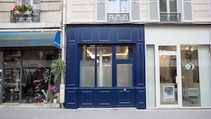 A building with a blue facade, a visible storefront with a sign, and a window with a poster. - Le Cafe des Invalides - Eiffel Tower (Paris)