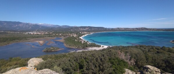 A coastal landscape with a clear view of the sea, a beach, and a town in the background. - GARDEN VILLA 3 MINUTES WALK FROM CALA ROSSA BEACH - RESIDENCE MARINA ROSSA (Lecci)