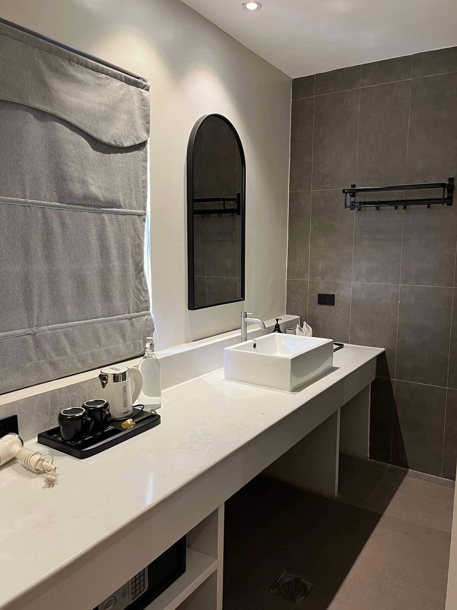 A modern bathroom with a white sink, a mirror, and a towel rack.