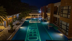 A nighttime view of a swimming pool with a 'NO DIVING' sign, surrounded by buildings and palm trees. - Only Seed Resort (Panglao)