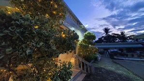 A building with a stone facade, a staircase, and a well-lit garden area with trees and lights. - Only Seed Resort (Panglao)
