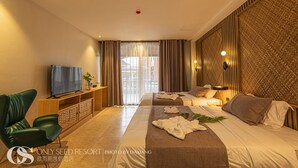 A hotel room with a bed, a TV, a desk, and a green chair. - Only Seed Resort (Panglao)