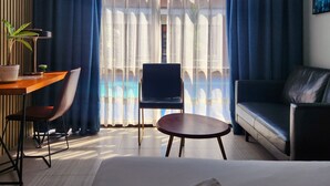 A hotel room with a bed, a desk, a chair, a sofa, and a view of a pool. - Only Seed Resort (Panglao)