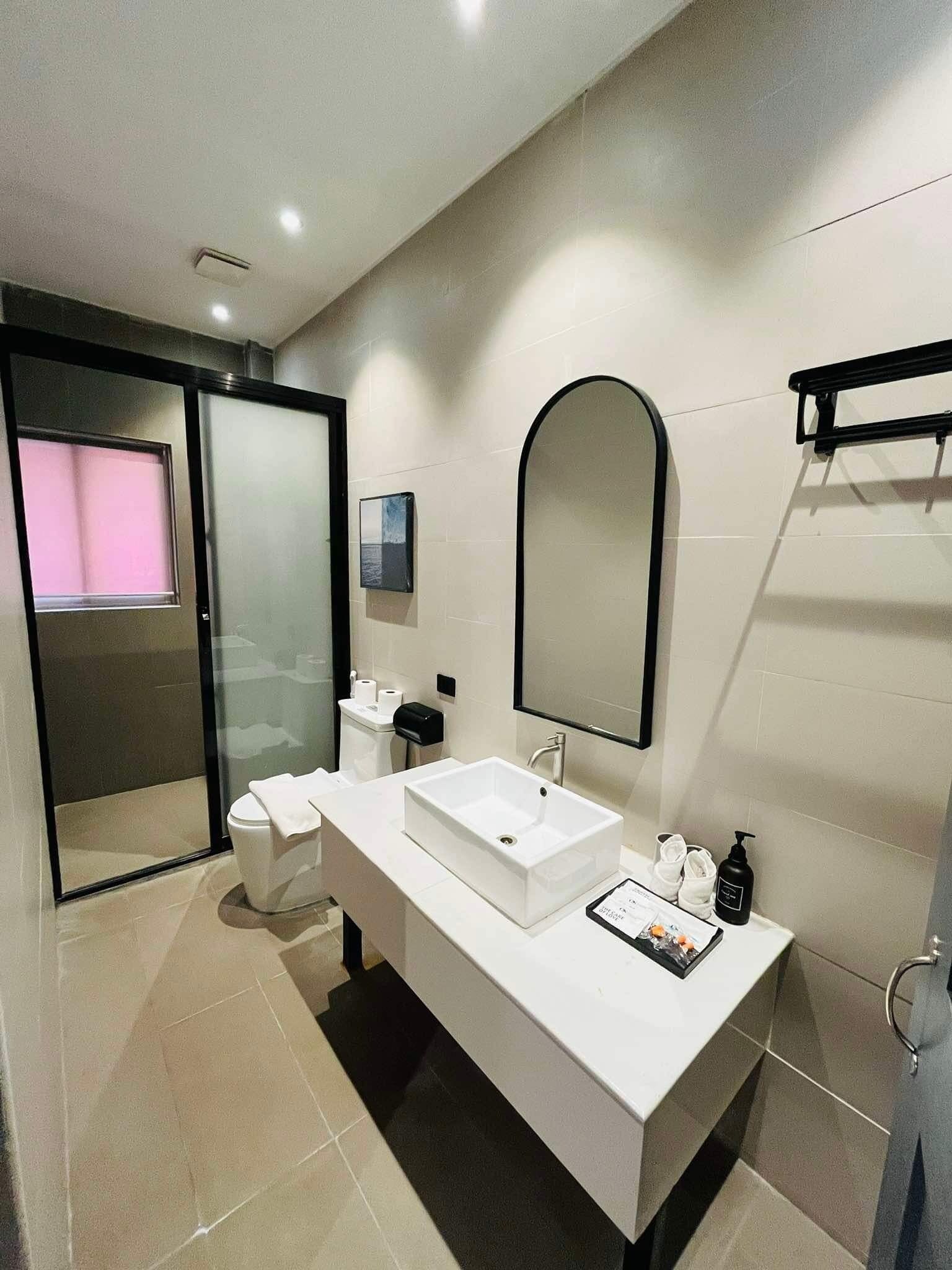 Un baño moderno con tocador blanco, un espejo grande y una cabina de ducha de vidrio.