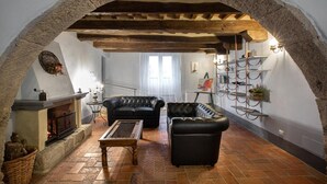 A cozy living room with a fireplace, leather sofas, a coffee table, and a stone archway. - B&B Gli Archi (Abbadia San Salvatore)