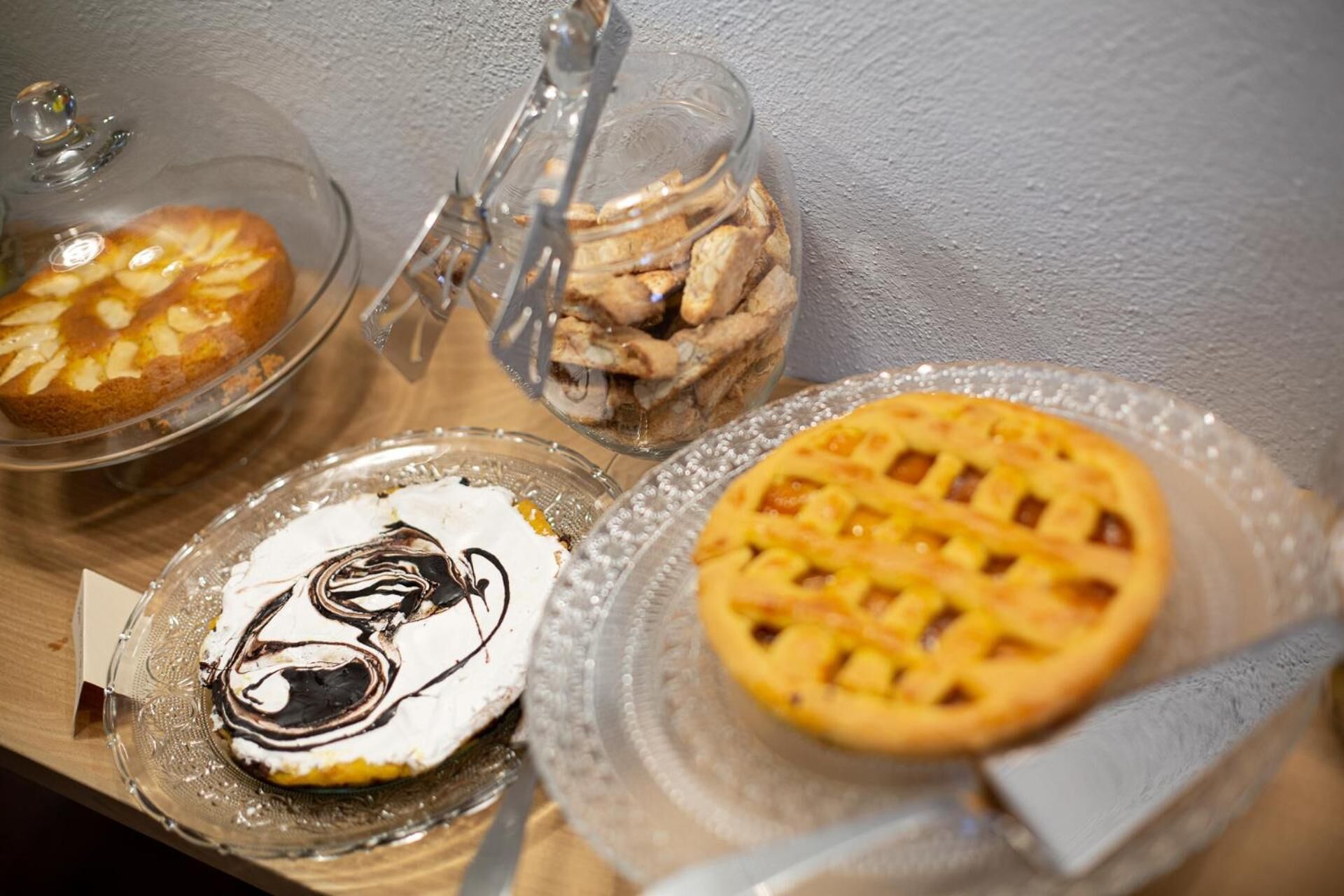 Un vassoio con tre dolci: una torta con copertura a reticolo, una crostata con impasto a griglia e un'altra crostata con crema sbattuta e salsa al cioccolato.