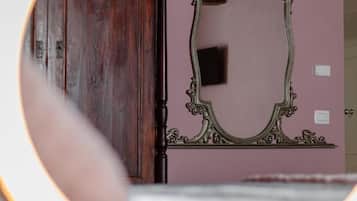 A mirror with an ornate frame, a wooden wardrobe, and a pink wall.