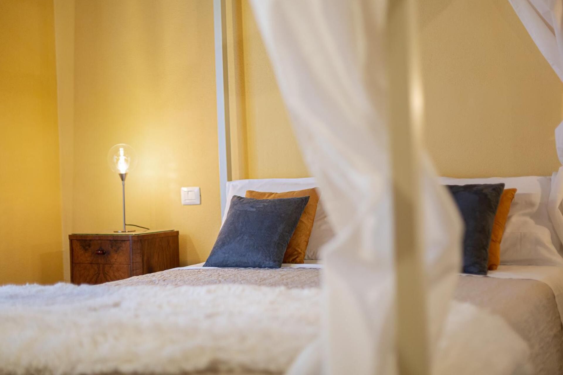 Une chambre à coucher avec un lit à baldaquin, une table de chevet avec une lampe et une commode.