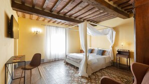 A bedroom with a four-poster bed, a desk with a chair, and a piano. - B&B Gli Archi (Abbadia San Salvatore)
