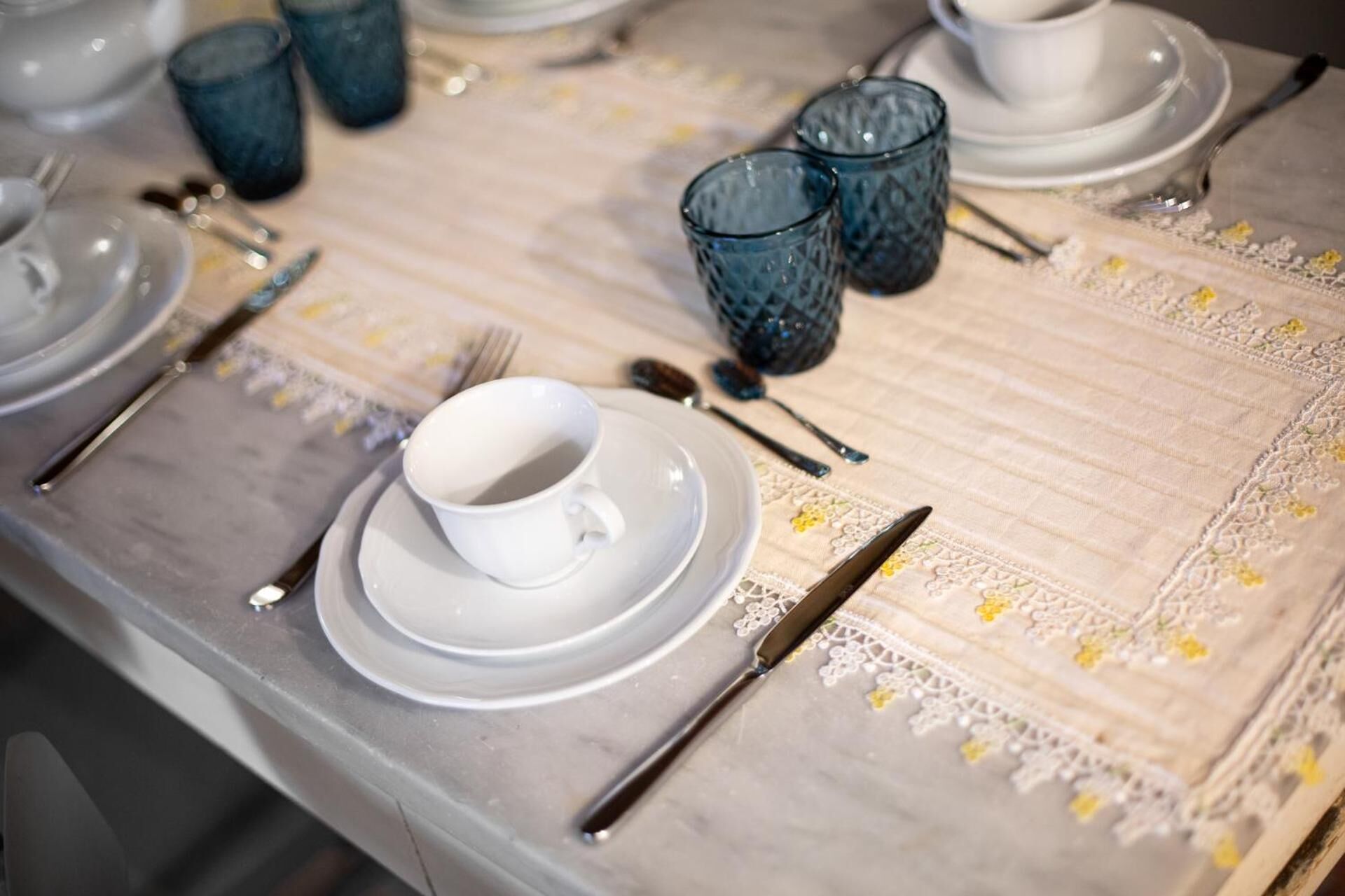 Une table dressée avec de l’argenterie, de la vaisselle bleue et des assiettes blanches.