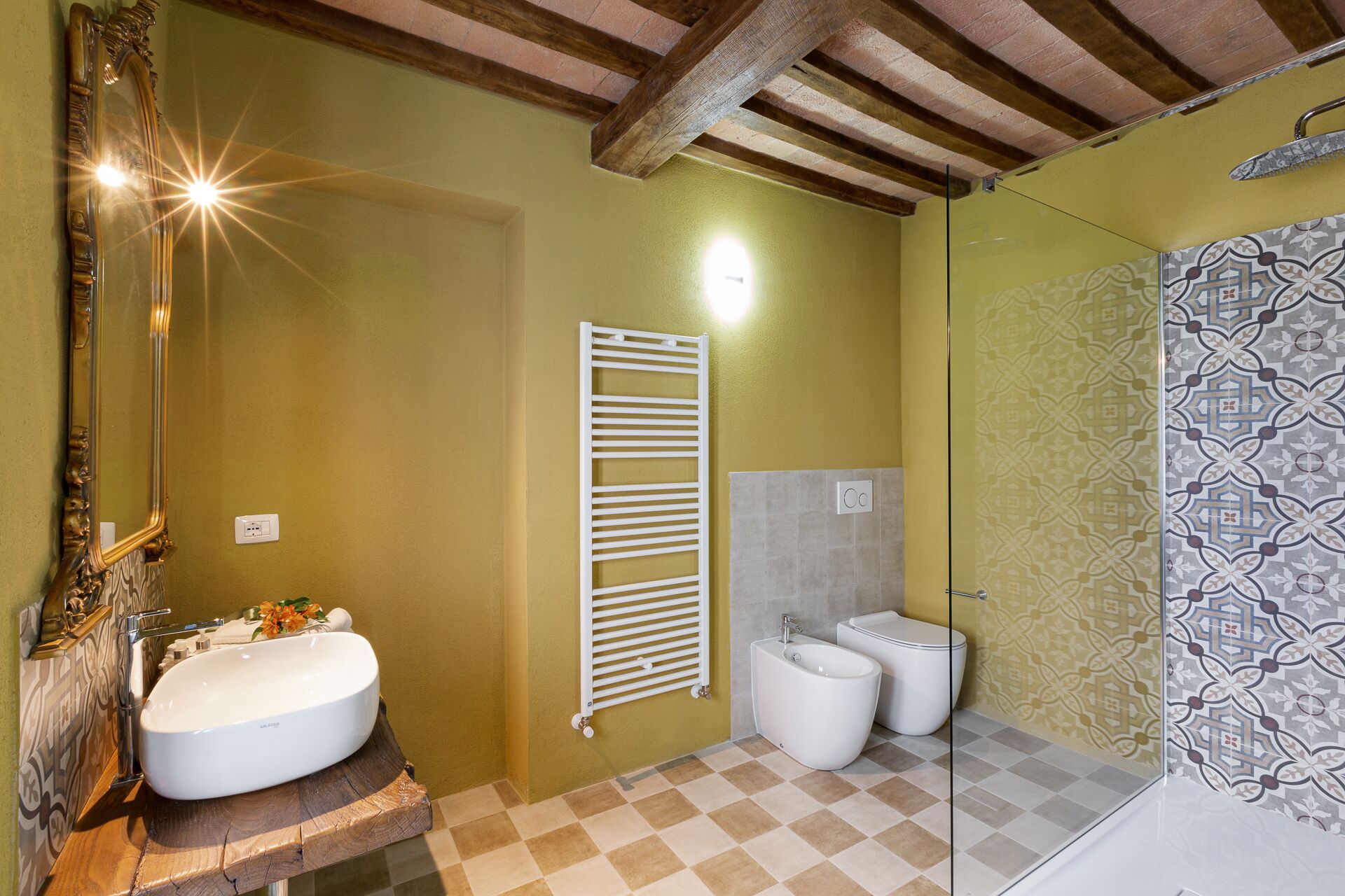 Un bagno con un mobile bagno in legno, uno specchio grande, un portascopevoli, un water e uno spazio doccia.