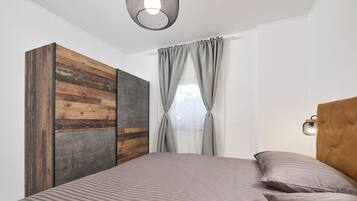 A bedroom with a bed, a wardrobe, and a window with curtains.
