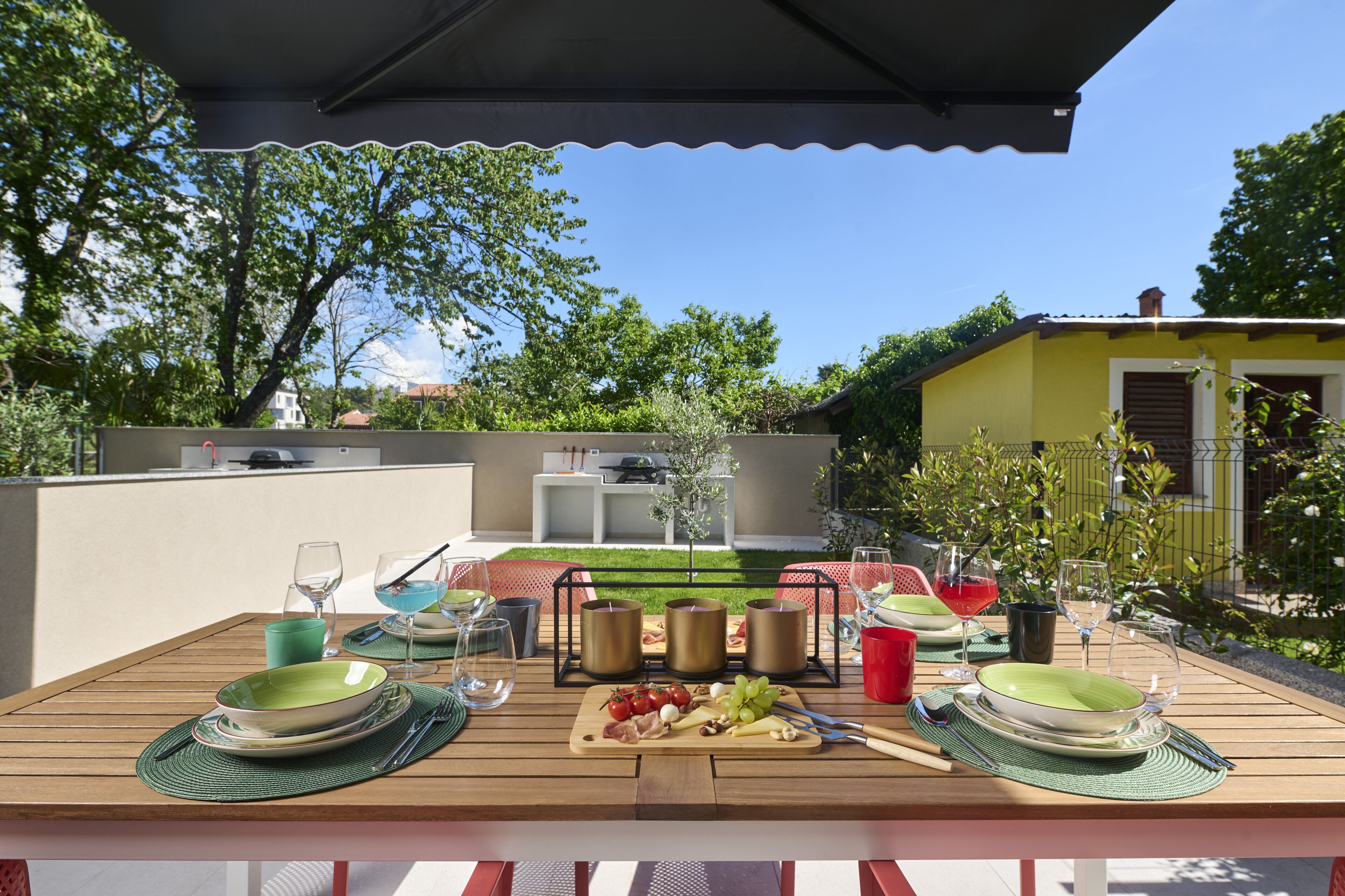 An outdoor dining area with a table set for four, including plates, cutlery, and glasses.
