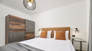Quarto moderno com cama grande, painel de madeira e mesinha de vidro.