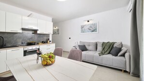 Uma cozinha moderna com armários brancos, bancada de mármore e área de refeições com mesa e cadeiras.