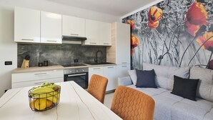 Uma cozinha moderna com armários brancos, painel de fundo de mármore e um espaço de jantar com mesa e cadeiras.
