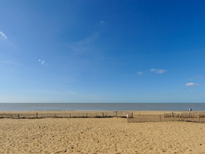 A sandy beach with a wooden fence in the foreground and a clear blue sky. - Cozy 1BR Apartment with Balcony, 50m from Beach, Near Shops & WiFi (Châtelaillon-Plage)