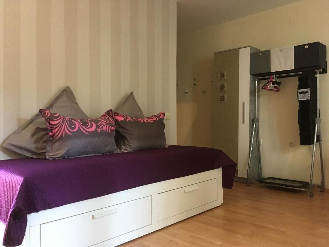 A bedroom with a bed, pillows, a white dresser, and a wardrobe.