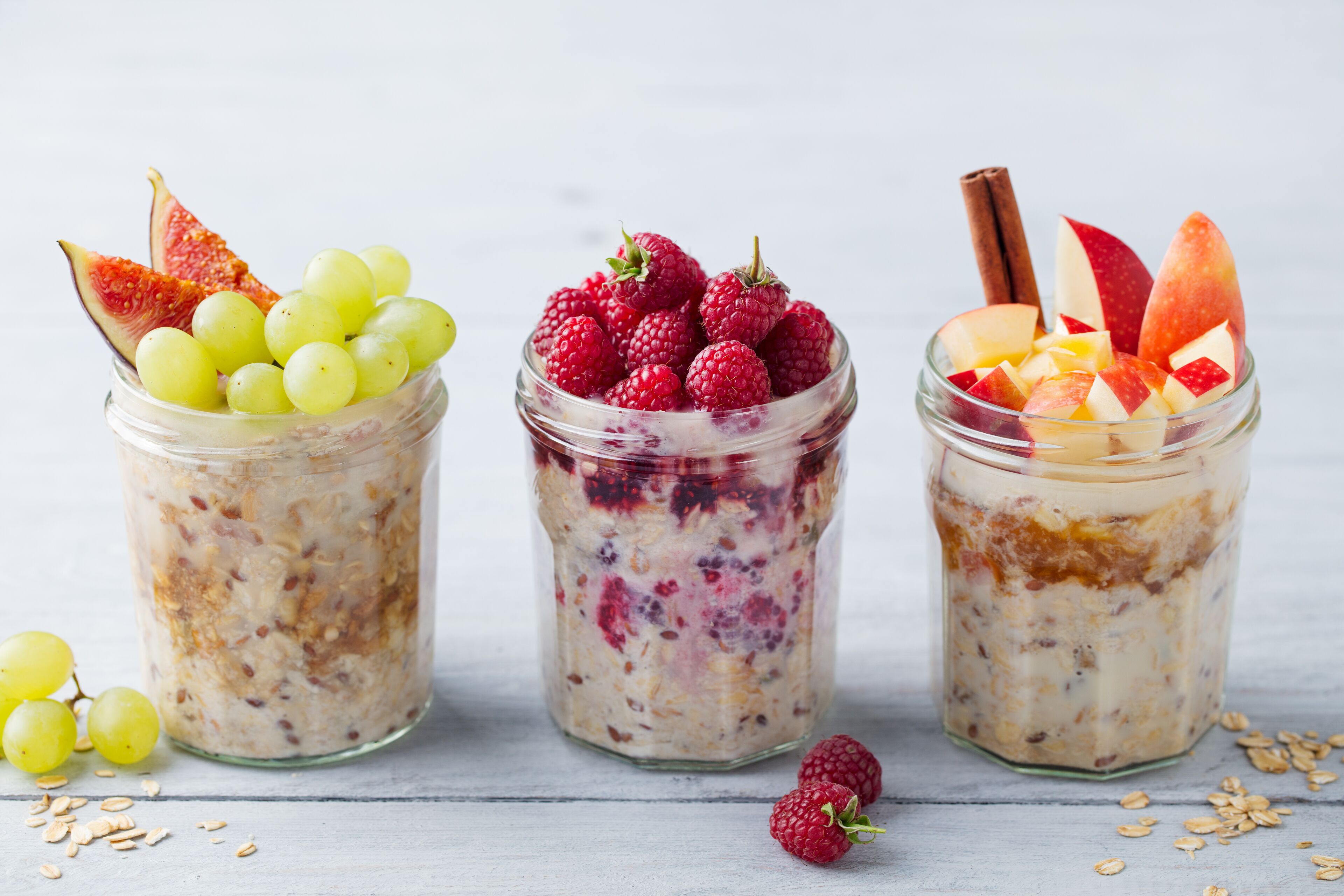 Three glass jars containing oatmeal with different fruits.