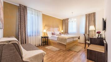 A hotel room with a wooden bed, a desk, a chair, and a TV.