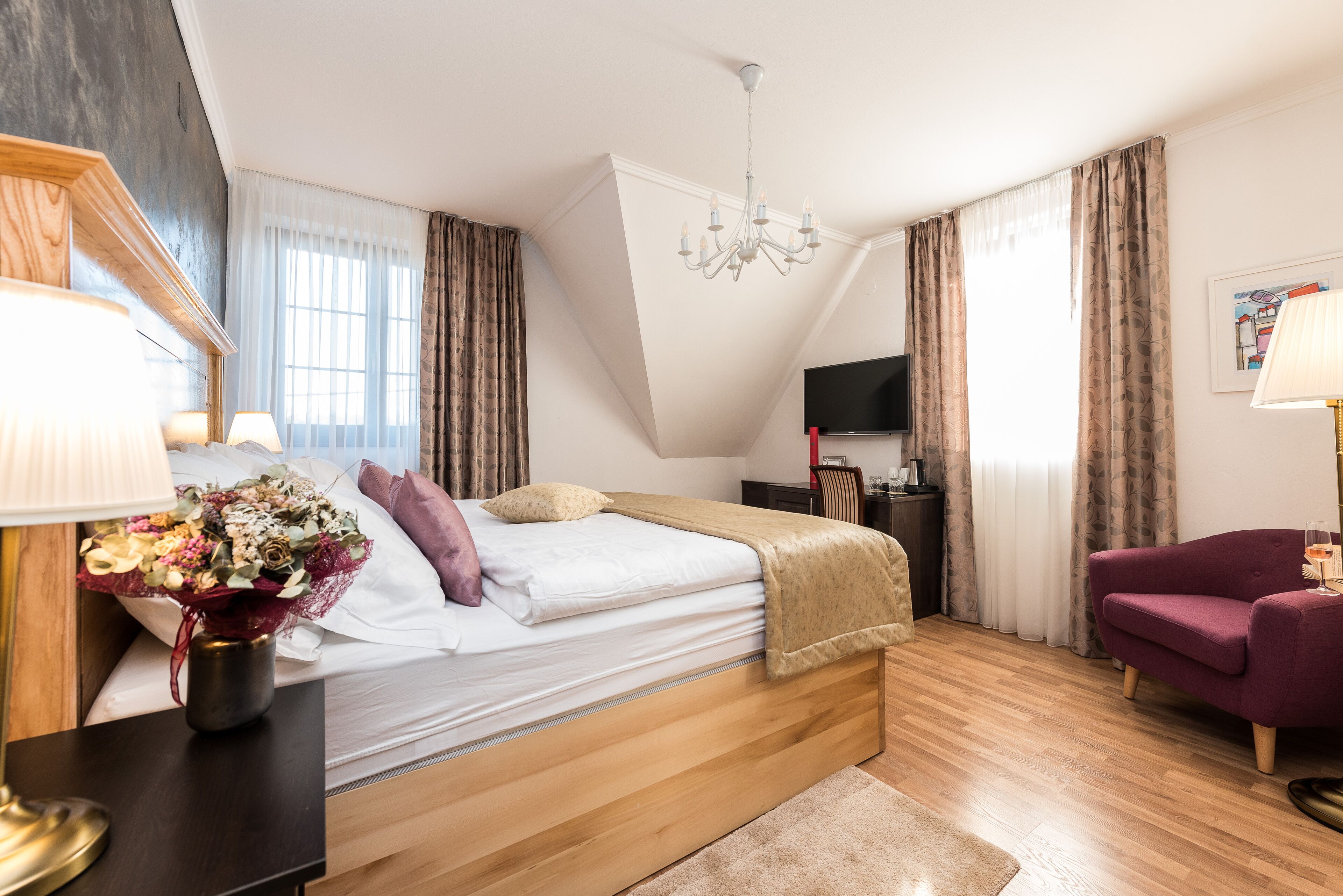 Un dormitorio moderno con una cama de madera, un televisor, un escritorio y un sillón morado.