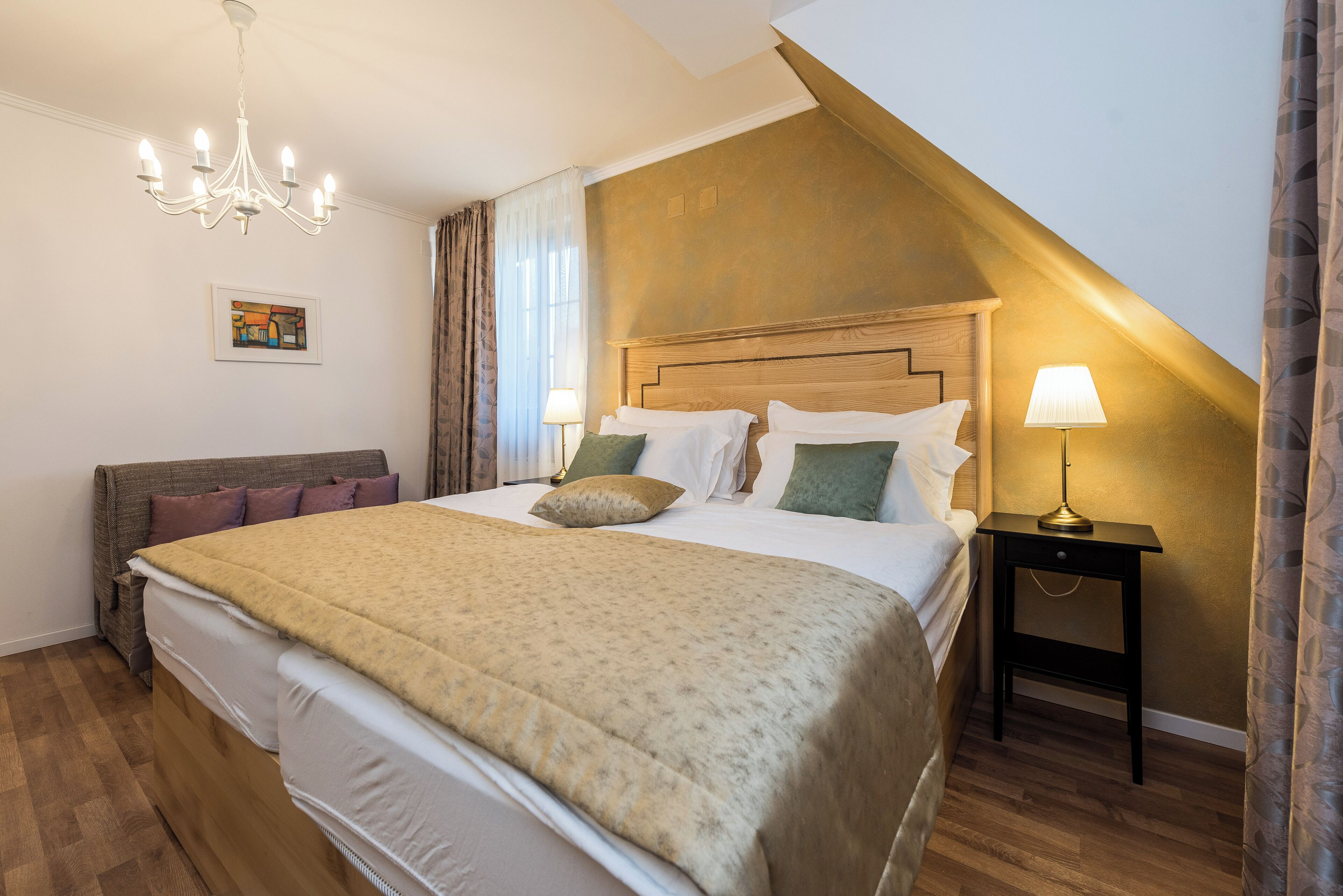 Une chambre à coucher avec un grand lit, un lustre, une table de chevet et un tableau au mur.