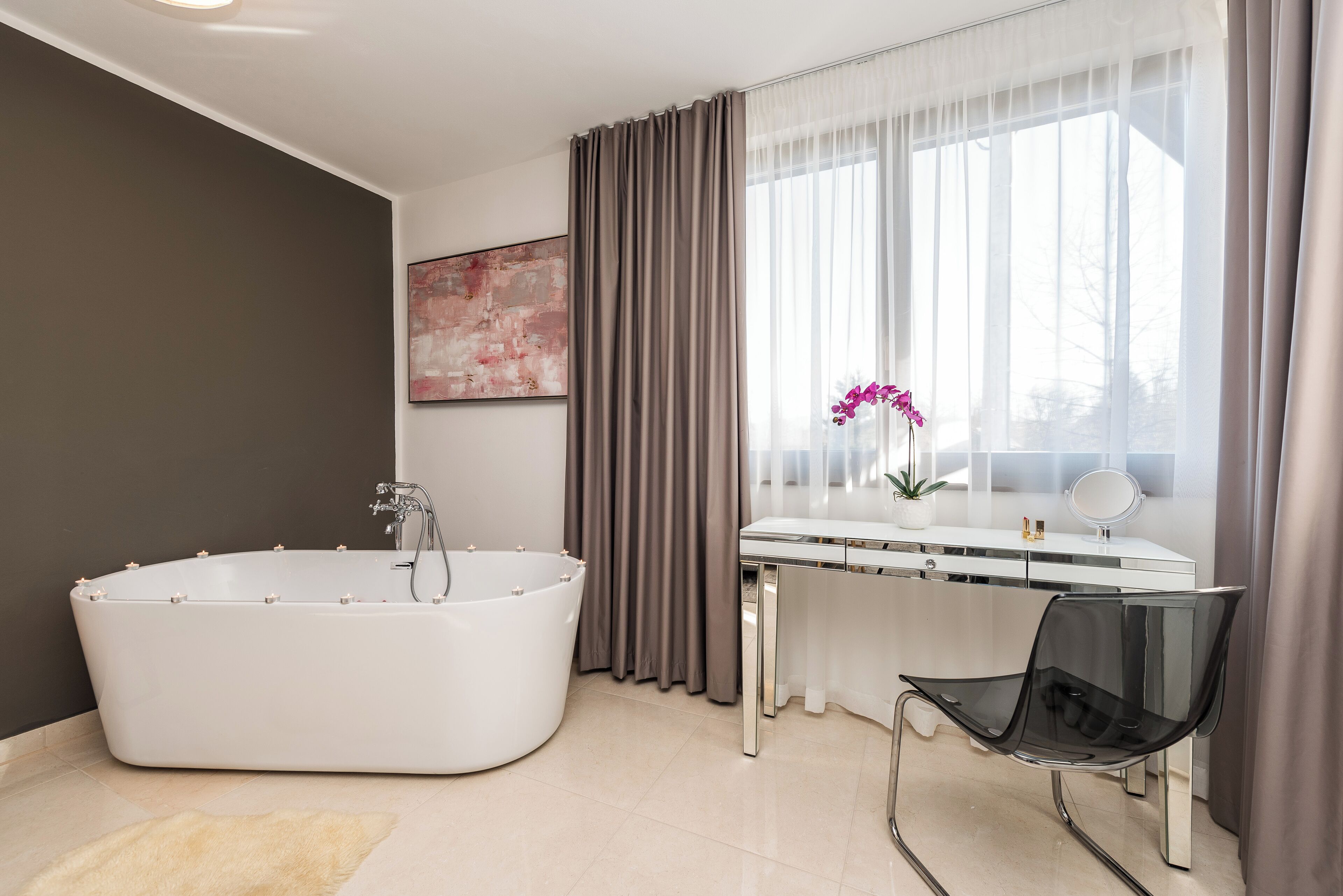 A modern bathroom with a freestanding bathtub, a vanity with a mirror, and a chair.