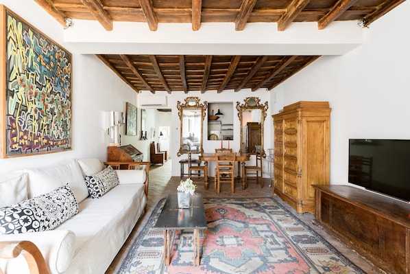 A living room with a sofa, coffee table, TV, wooden cabinet, and decorative mirrors.